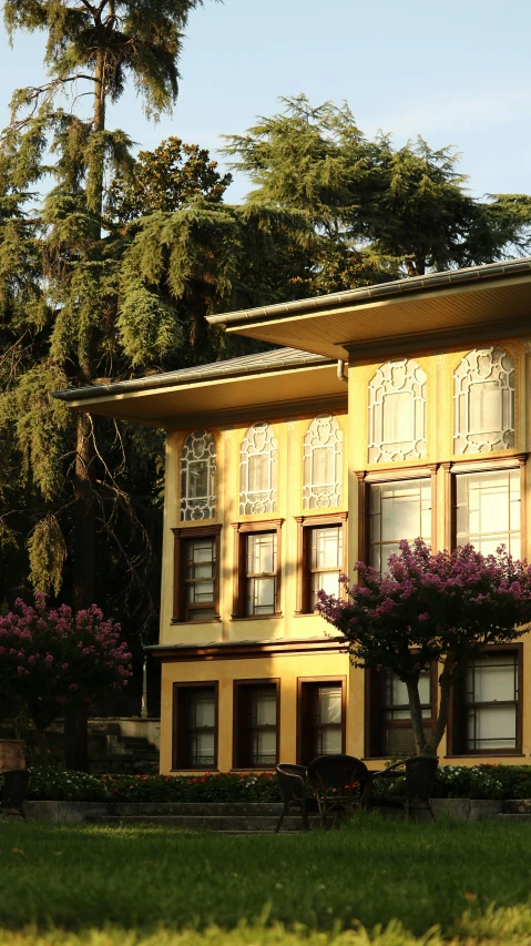 an orange two - story building with flowering trees in front of it