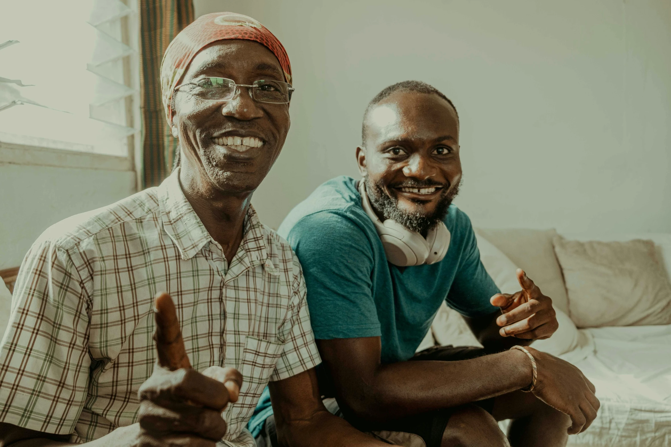 two men smiling while sitting on a couch