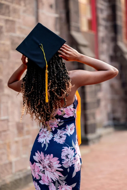a woman wearing a graduation hat stands outside
