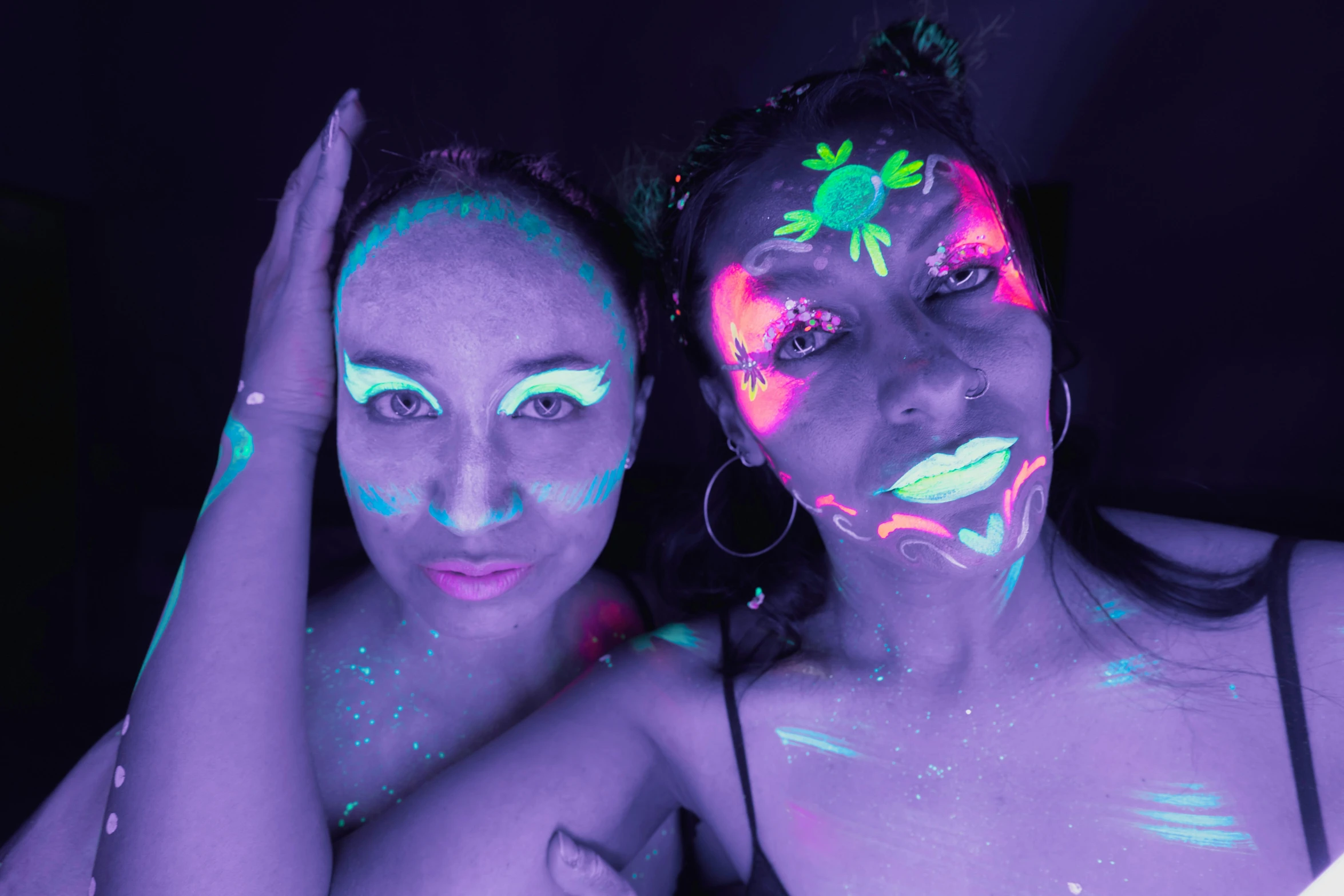 two women with neon powder on their faces and body