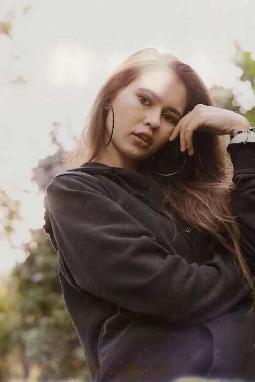 a woman with long hair is standing near trees