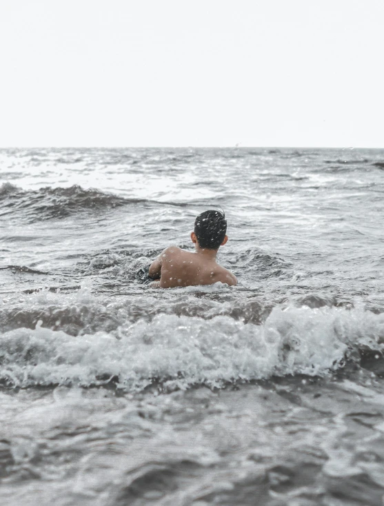 a man is swimming in the ocean on a surfboard