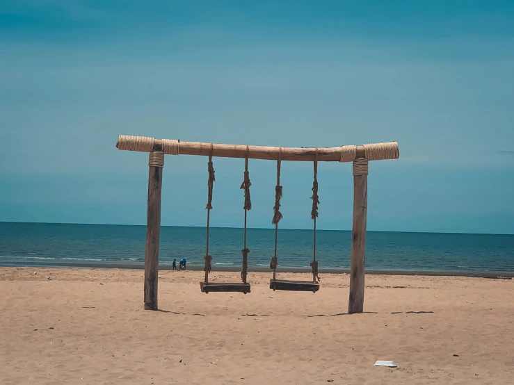 an empty swing and set of swings on the beach