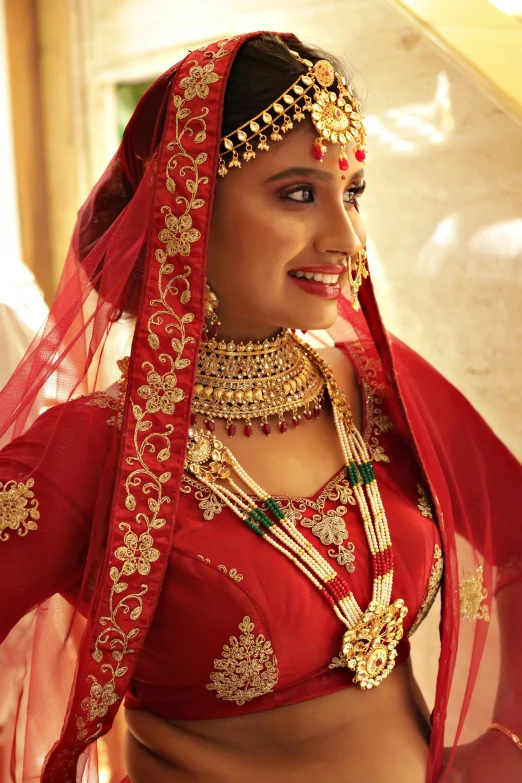 a woman dressed in a red wedding outfit wearing gold jewelry and accessories
