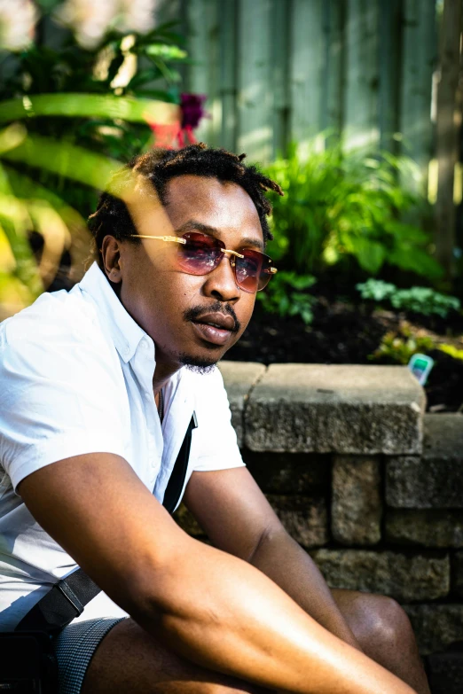 the man is sitting on a stone bench wearing sunglasses