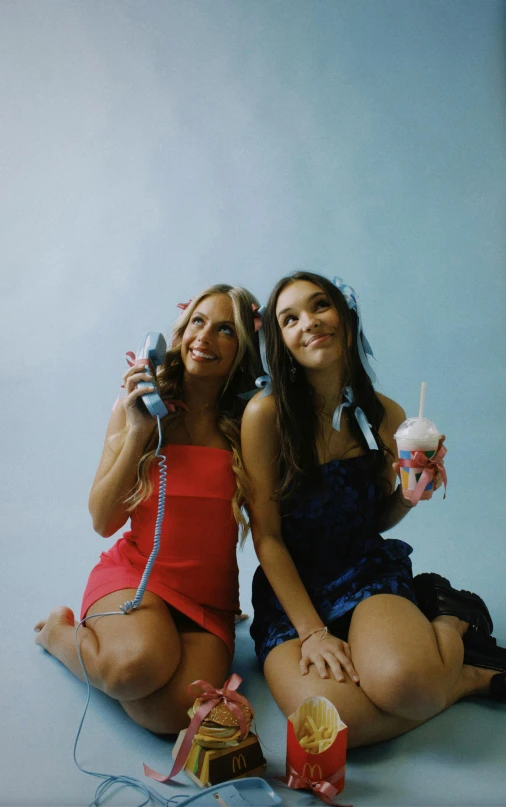 two girls sitting in the po on the ground with bags