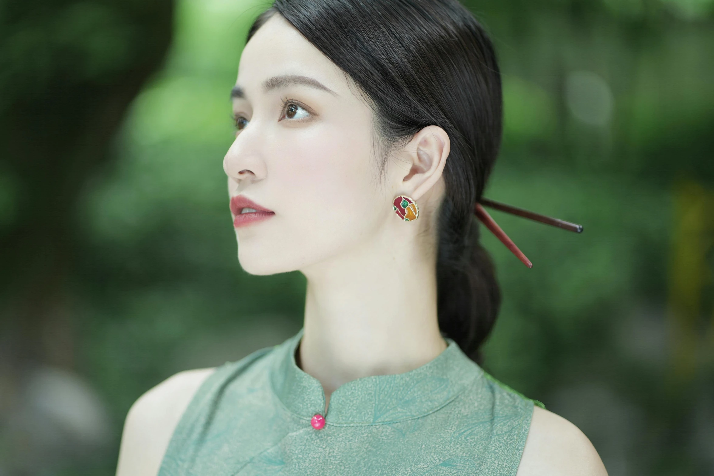 woman with black hair and green shirt and red earrings