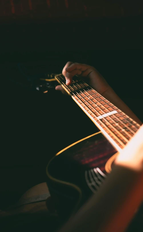 someone's hand on the string of an acoustic guitar