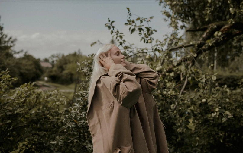 a person in a brown cloak standing by a tree