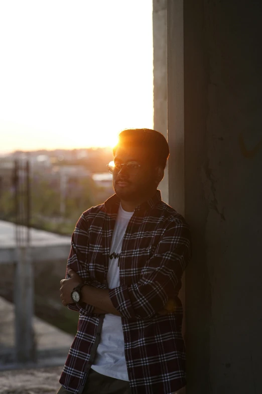 a man leaning against a wall near the sun