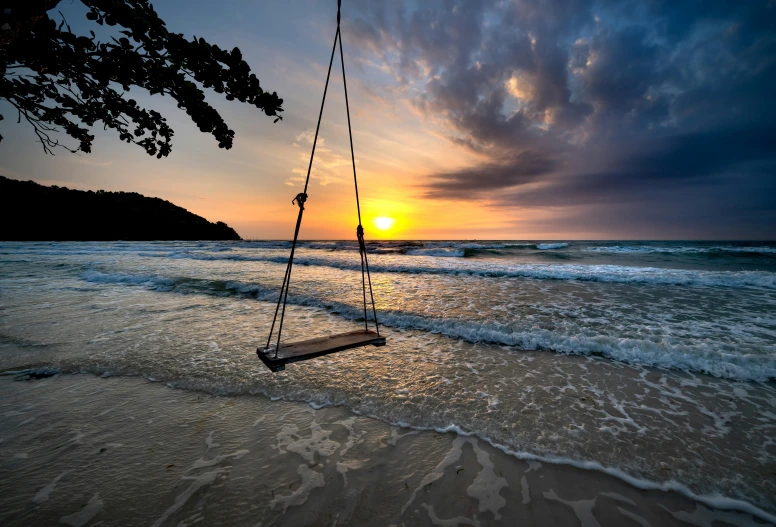 a swing on the beach is suspended to the water