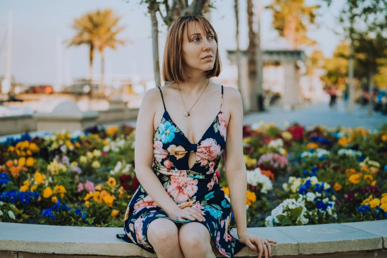 a woman sitting on top of a wooden wall near flowers