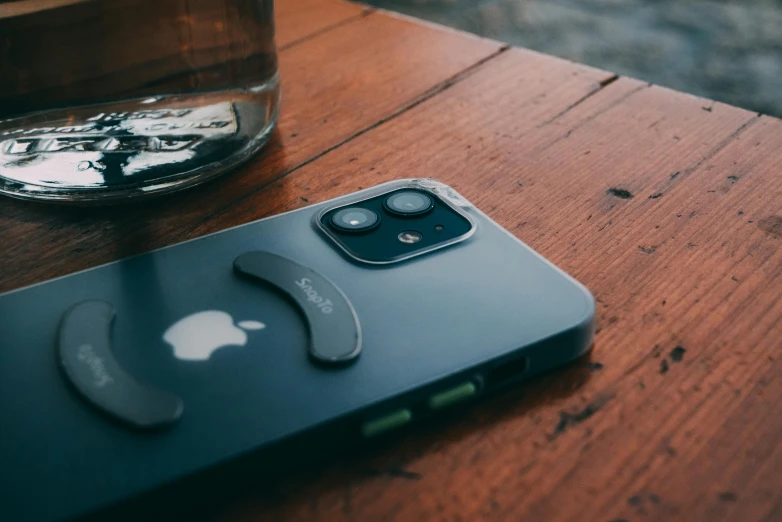 an iphone sitting on a table next to a glass