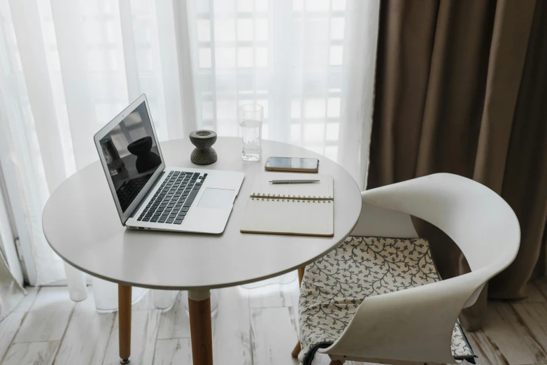 a laptop and pen on a small white table