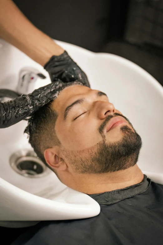 a man getting his hair brushed by someone with a hairdryer