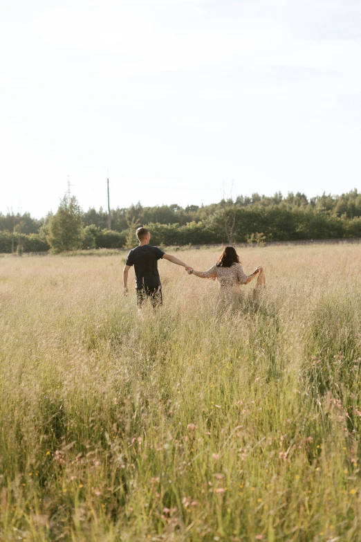 two people in a field holding hands with a kite