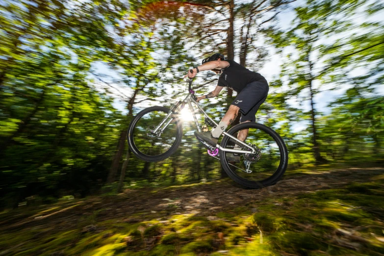 a man riding a bike through the air in a forest