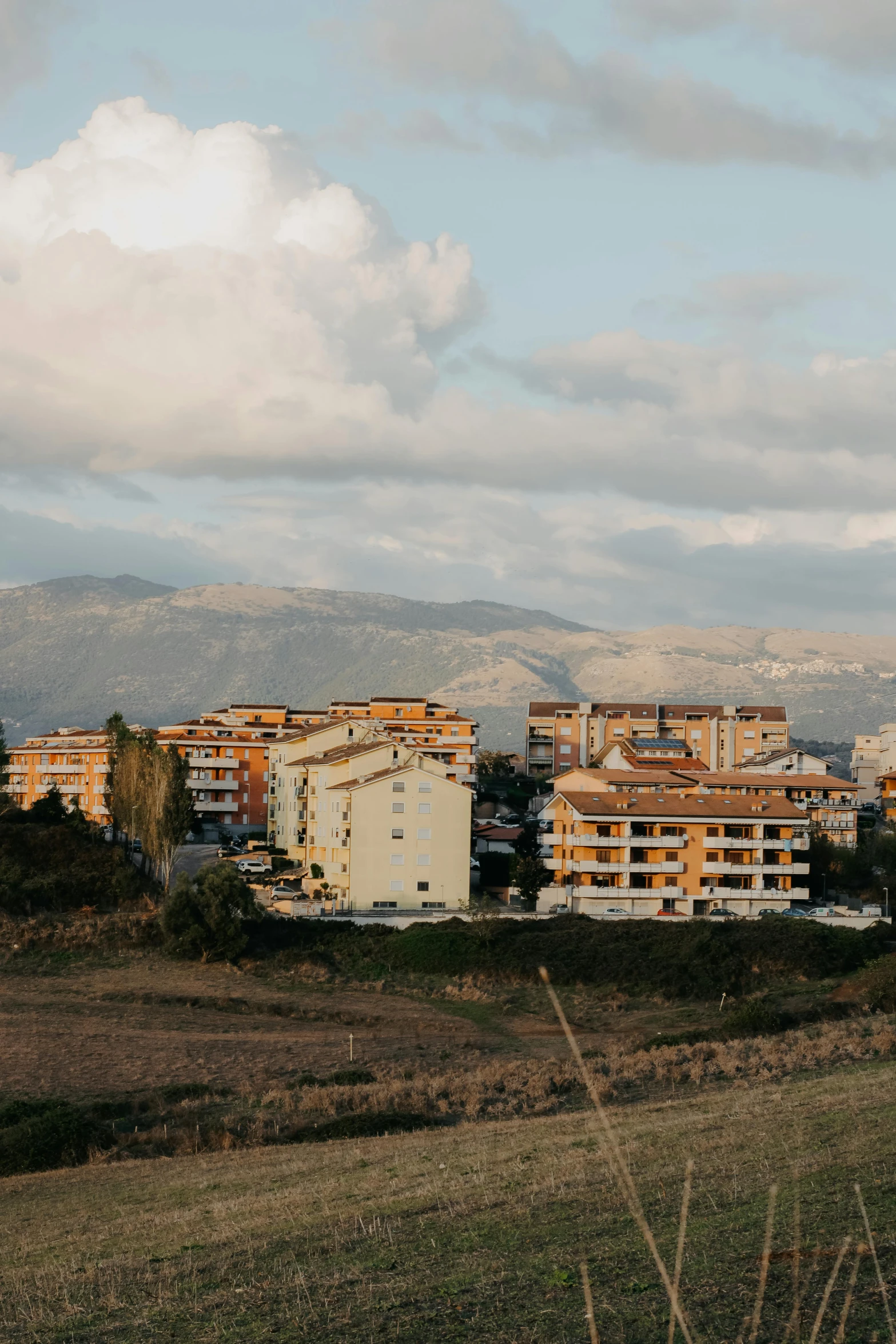 a city near some hills under clouds and mountain tops