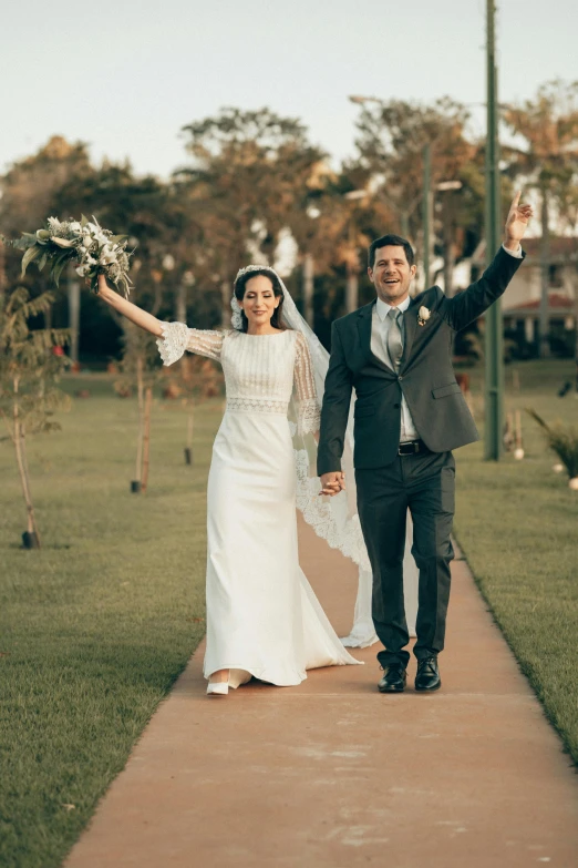 a bride and groom holding their hands while walking down the sidewalk