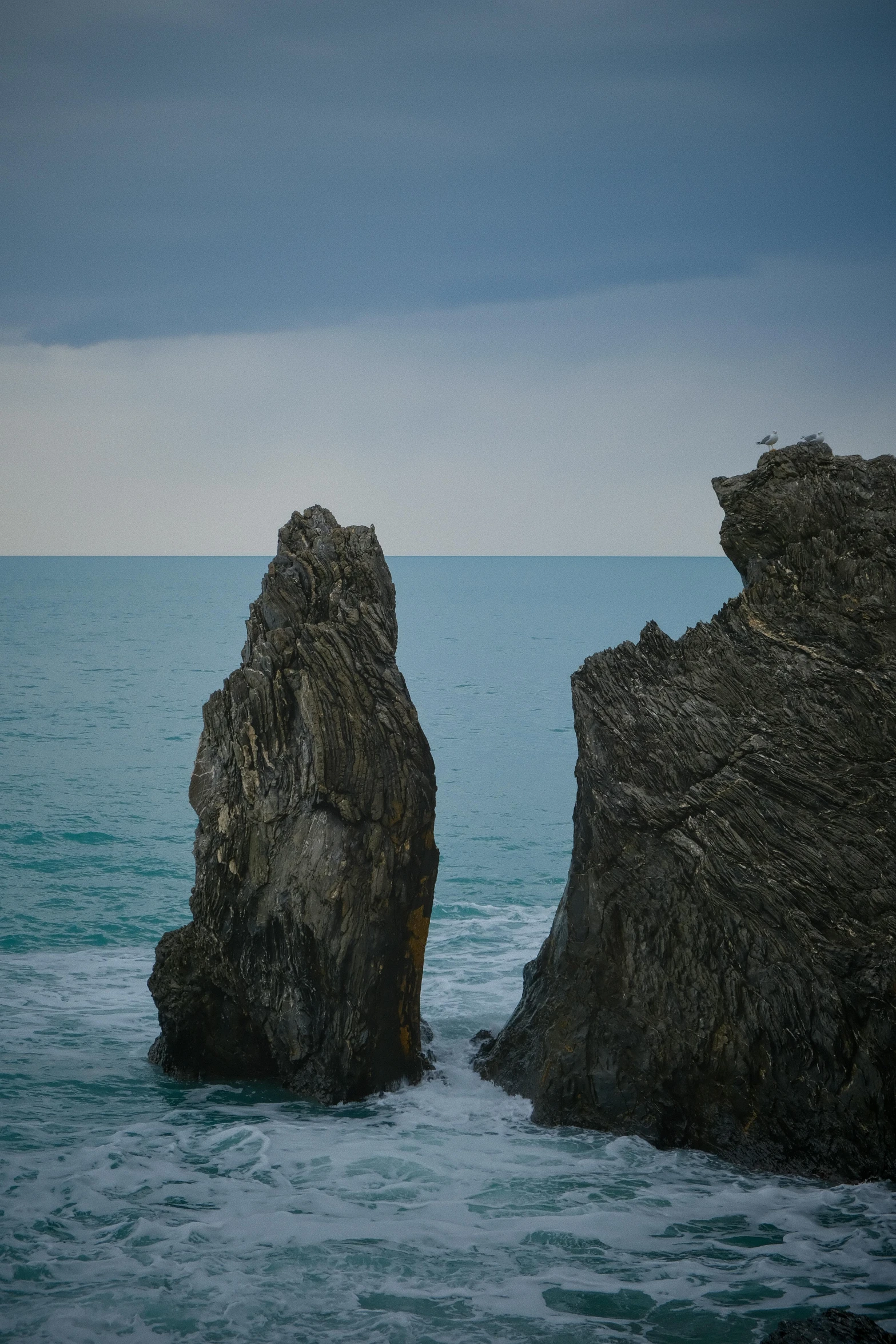 two rocks sticking out of the ocean from the shore