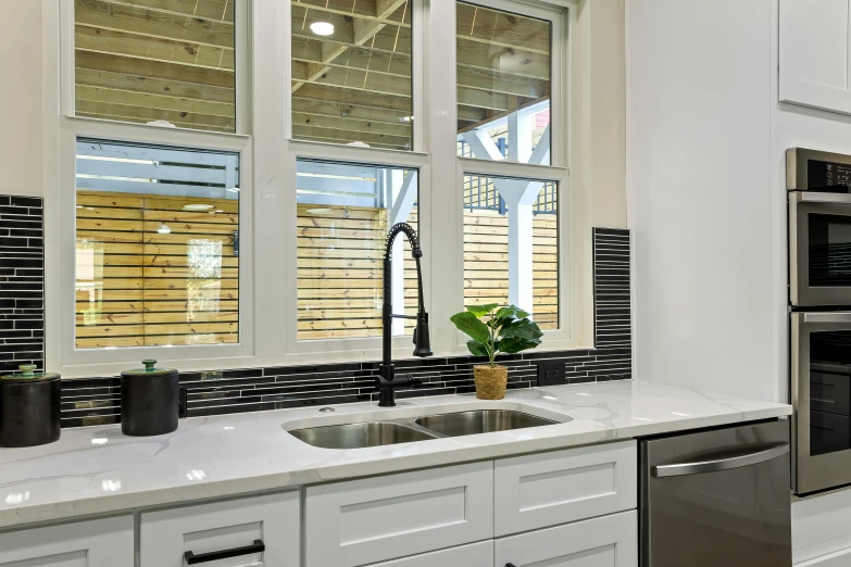 the kitchen has all white cabinets, stainless steel appliances, and black blinds