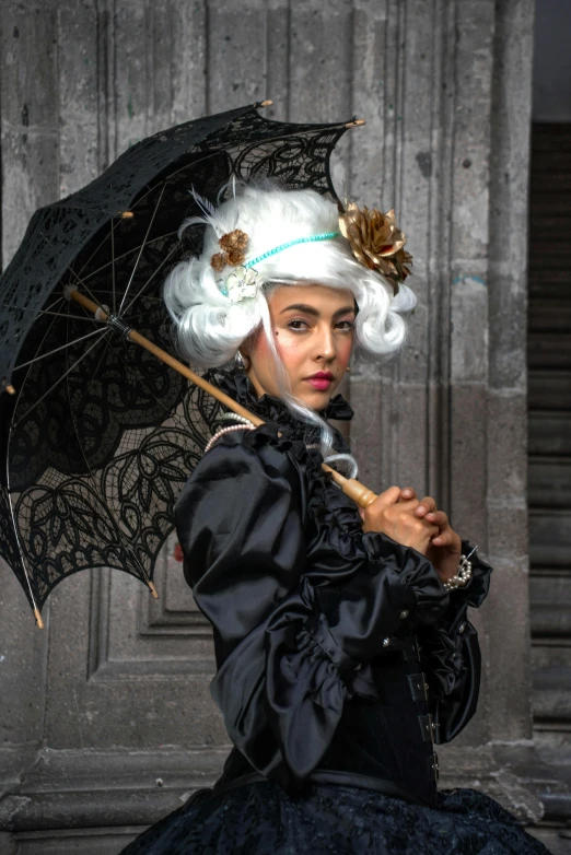 a woman with white hair wearing a black and blue dress holding an open umbrella