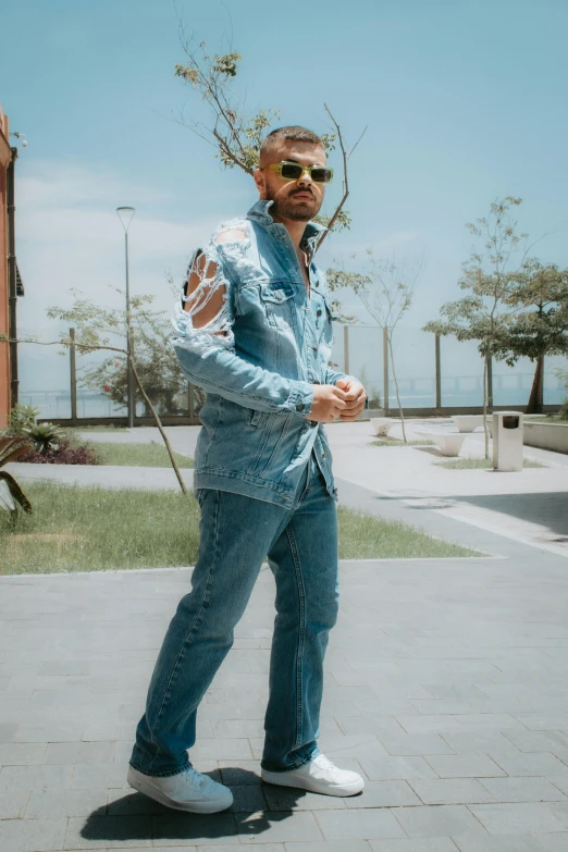 a man in jeans poses on the side walk