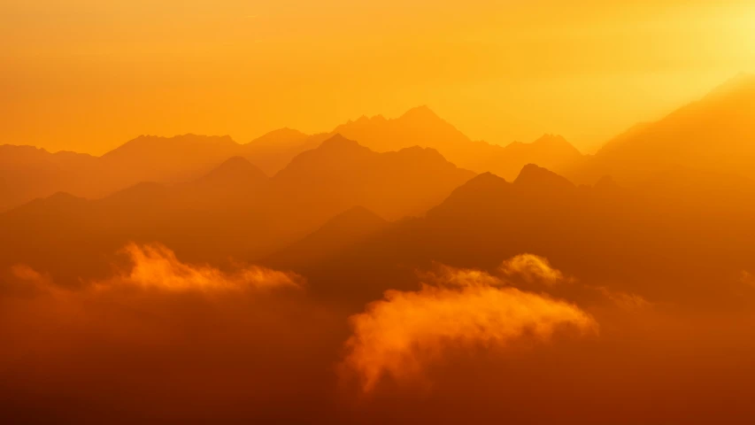 a view of mountains from a plane with a lot of fog in the air