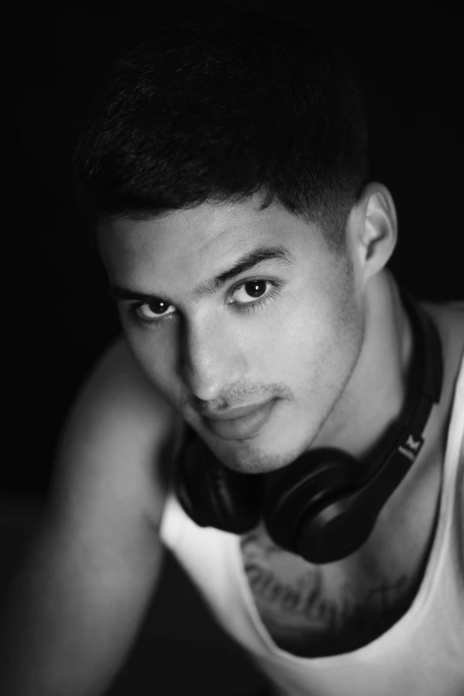 young man with hairdoodle, looking at camera while wearing headphones