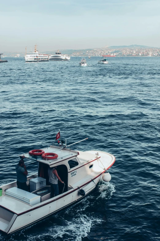 small boat in open sea surrounded by ships