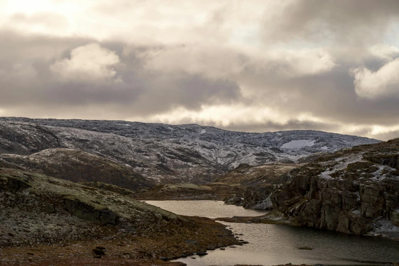 a snow covered mountain, a body of water and clouds