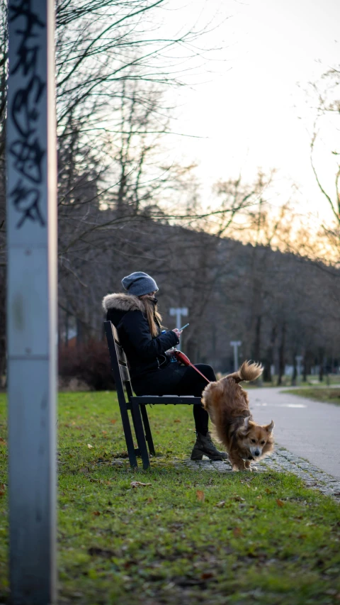 a woman is sitting on a chair outside, petting her dog