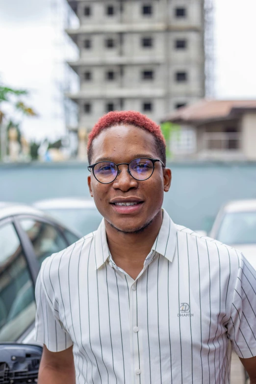 a male wearing glasses standing near parked cars