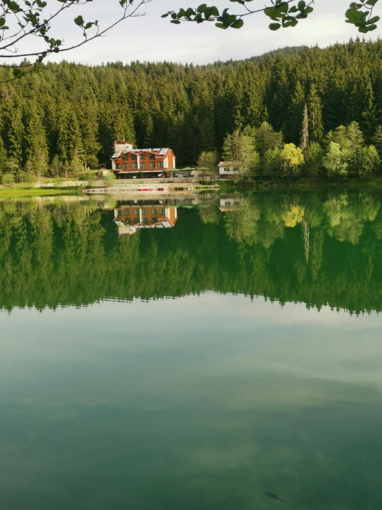 a house is on the edge of a lake surrounded by trees