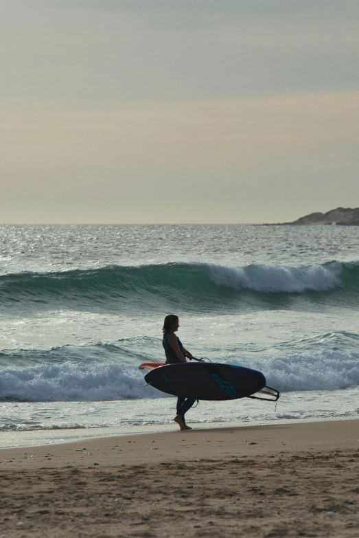 a man walking on the beach carrying a surfboard