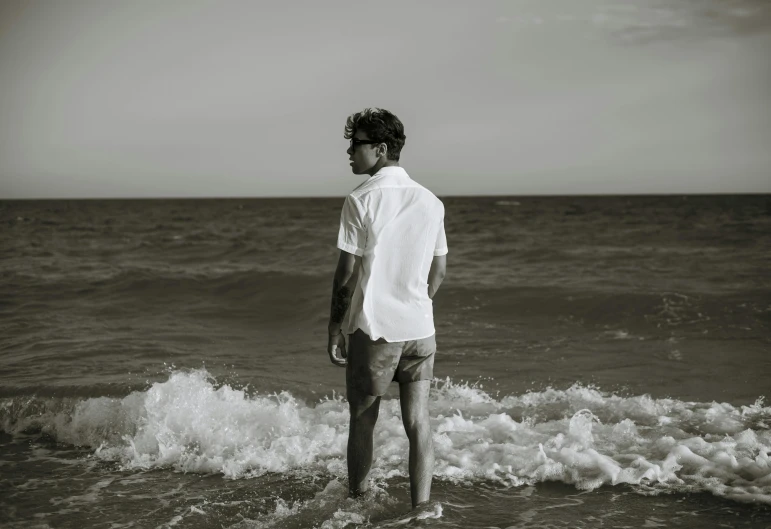 man stands on a beach with a frisbee near the ocean