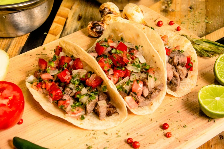 three tacos with meat, veggies and tomatoes on it