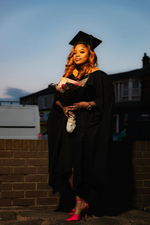 a woman in graduation attire holding her teddy bear