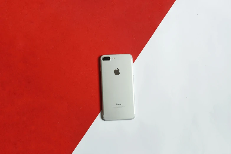 an apple iphone sits on top of a red and white color block