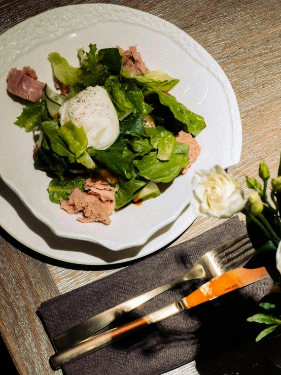 a white plate filled with salad next to a bowl of vegetables