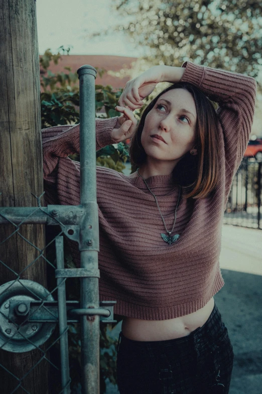 a girl is standing next to a chain link fence