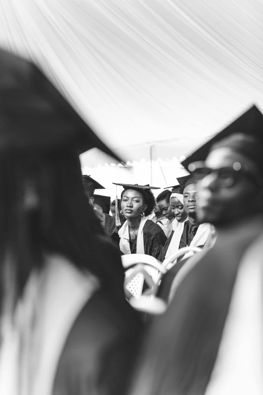 a group of students watching other graduates in graduation gowns