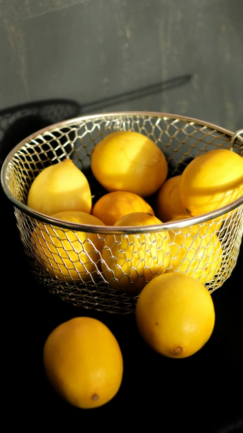 yellow lemons and a wire basket sitting on a counter