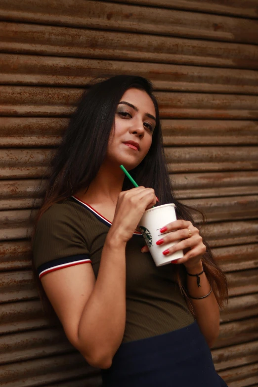 young woman drinking a beverage while holding a paper cup