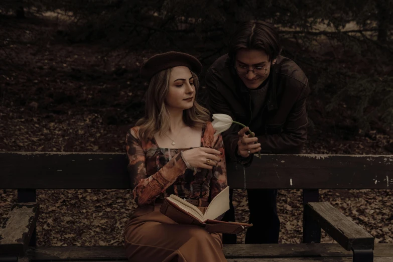 a man kneeling behind a woman while reading a book