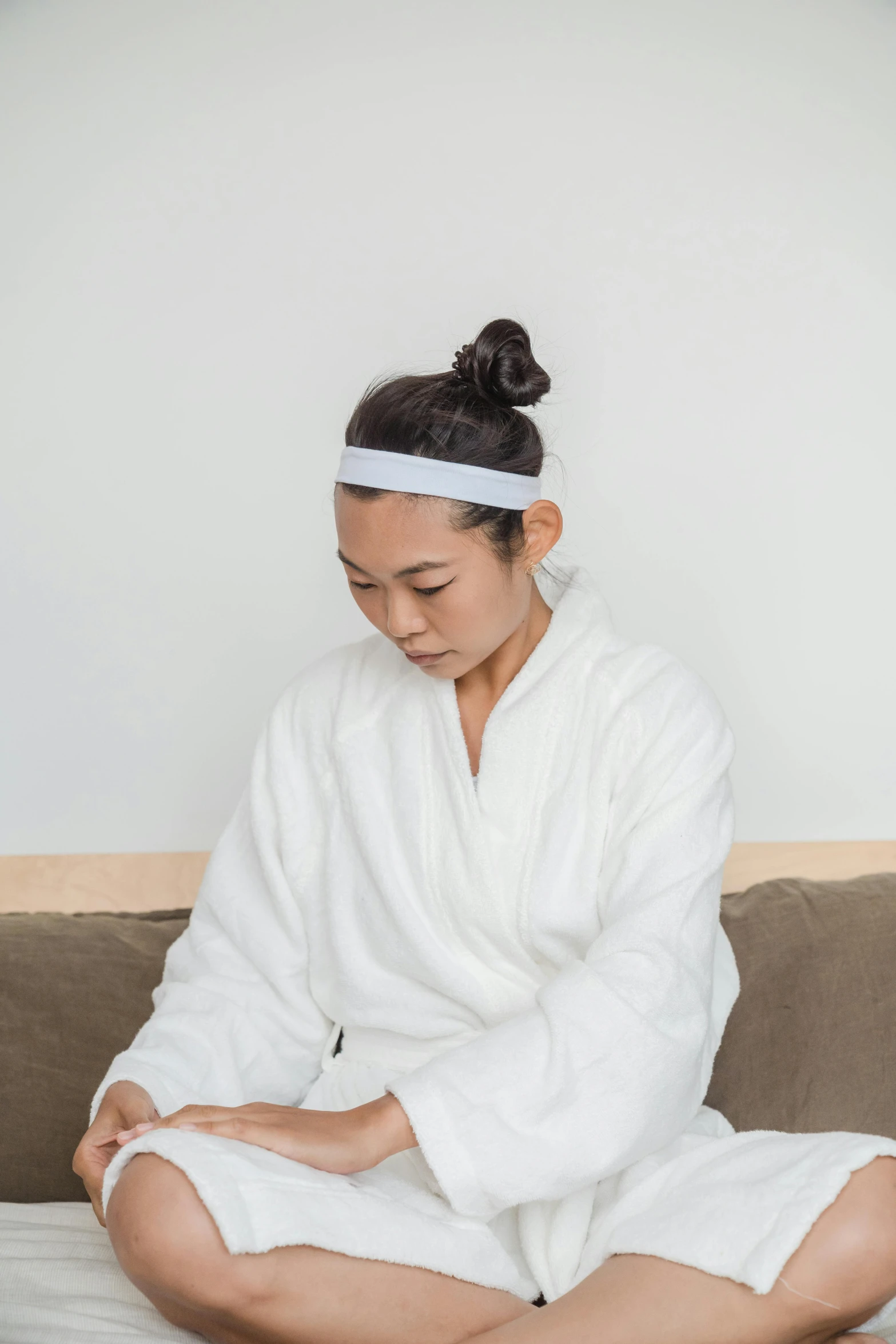 woman in white robe sitting on couch with headband on