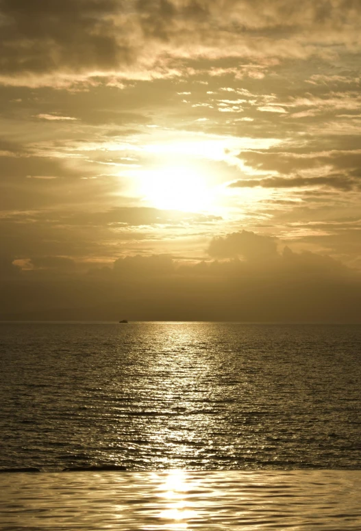 the sun setting behind the horizon of a large body of water