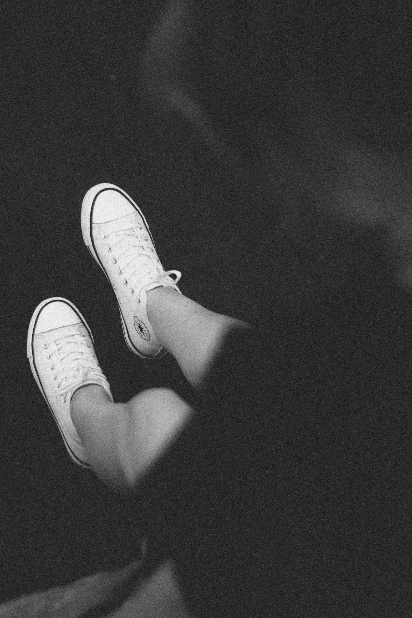 a person's legs and shoes as they lie in a dark room