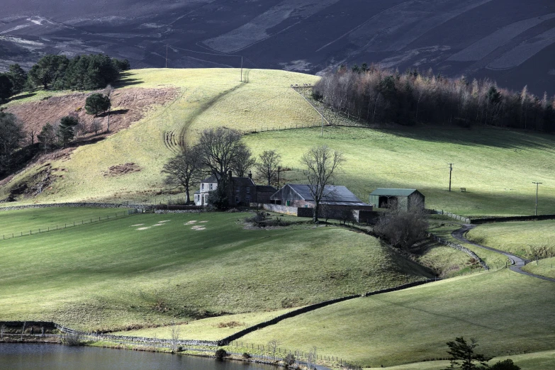 a grassy hill with a house and stream coming out