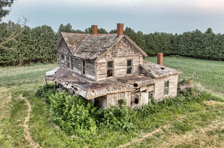 an old abandoned house sits in a green field